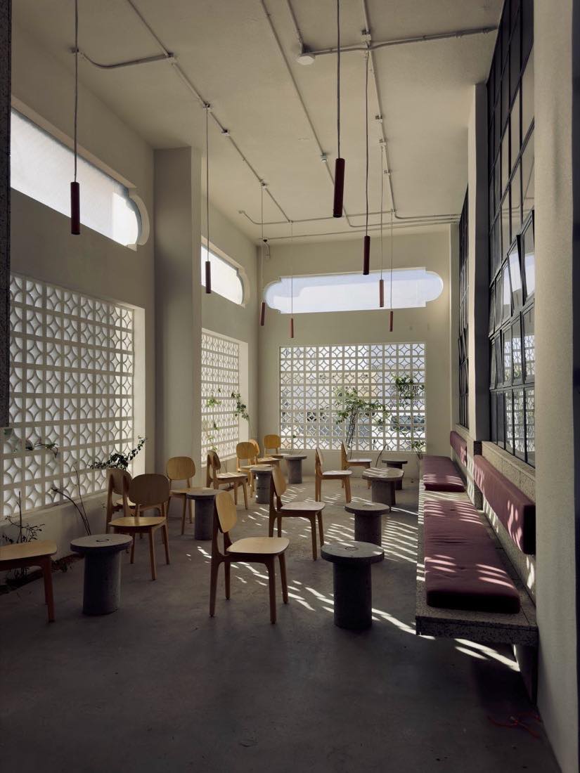 Breeze block jali lattice screens throwing dappled light across wood chairs inside Camel Step