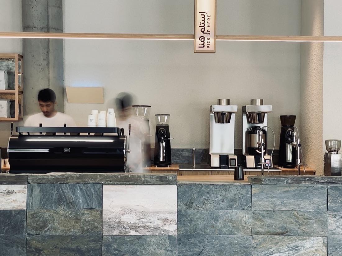 The Camel Step coffee bar in sage green stone with espresso machine and a pick up here sign